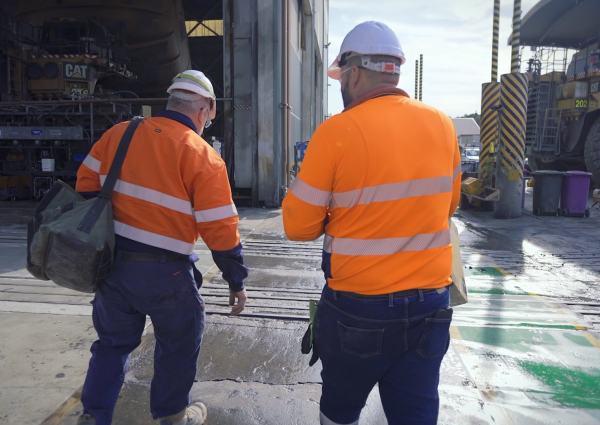 Two Total Fire Solutions team members walking on site wearing protective high-visibility safety gear.